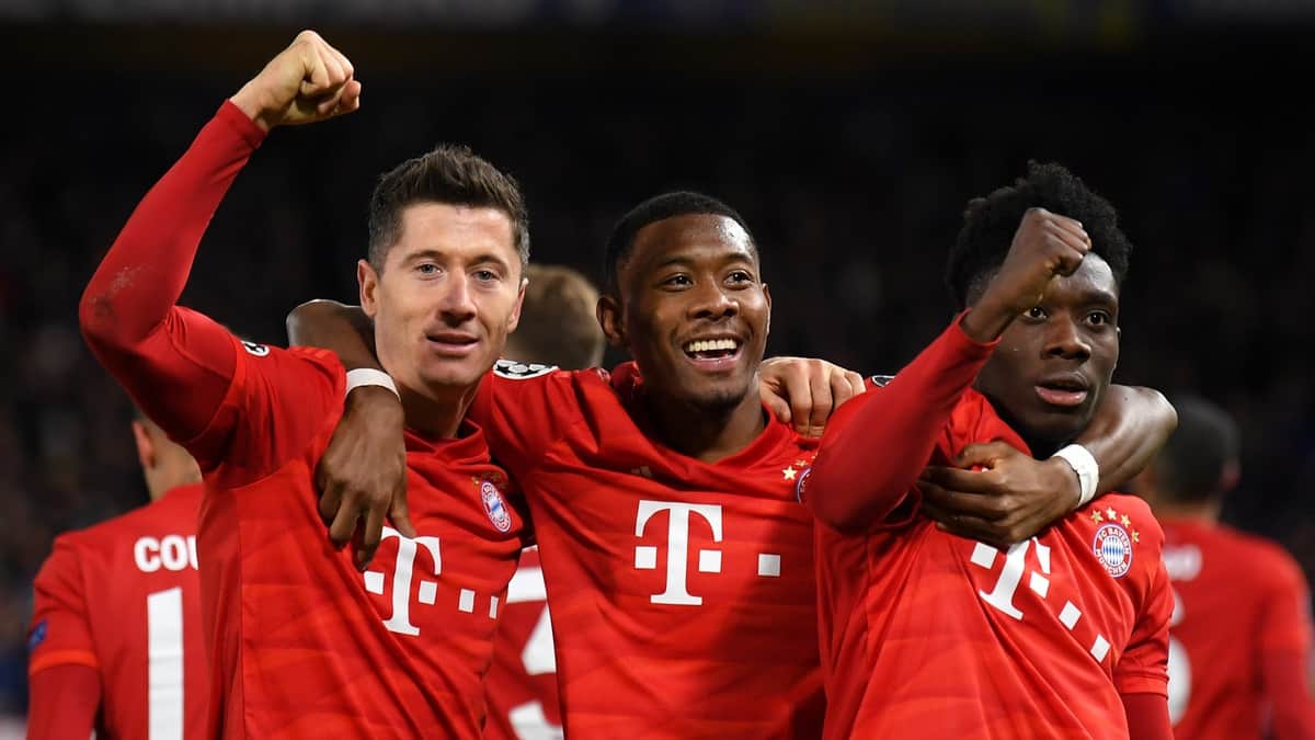 Robert Lewandowski of Bayern Munich celebrates with David Alaba and Alphonso Davies after he scores his team's third goal during the UEFA Champions League round of 16 first leg match between Chelsea FC and FC Bayern Muenchen